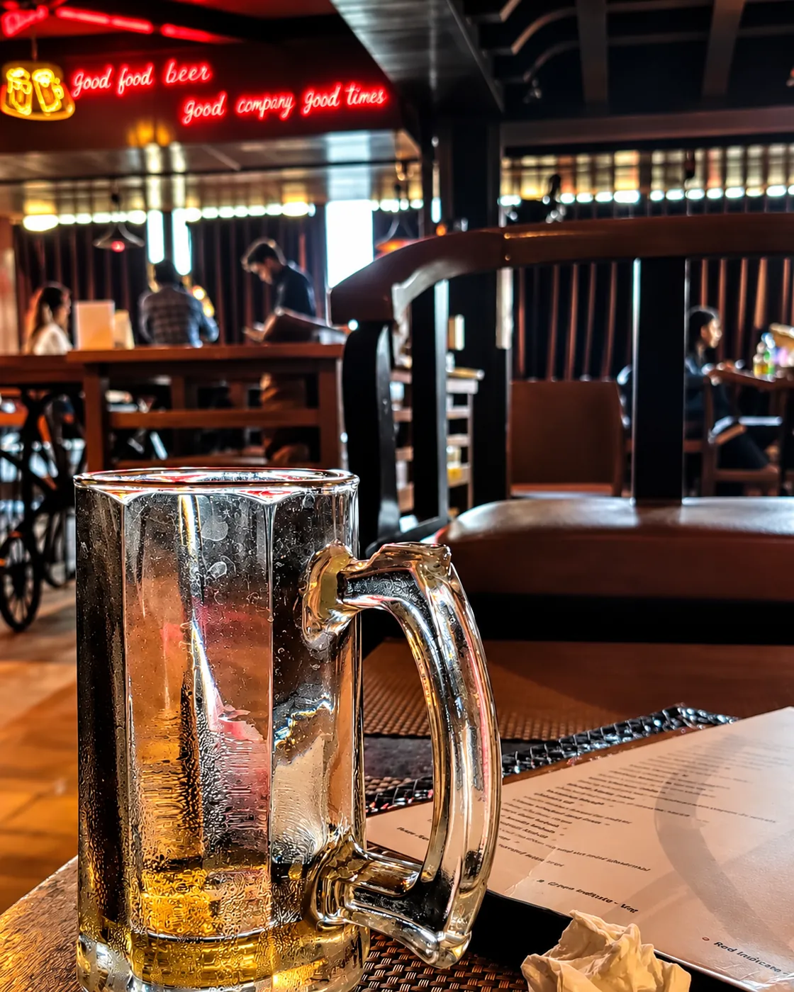 A chilled glass mug of beer at BAR CODE bar in Civil Lines, Prayagraj, with red neon behind it.